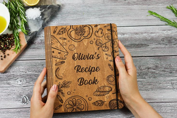 a pair of hannds holding a book with the  title olivia's recipe book
